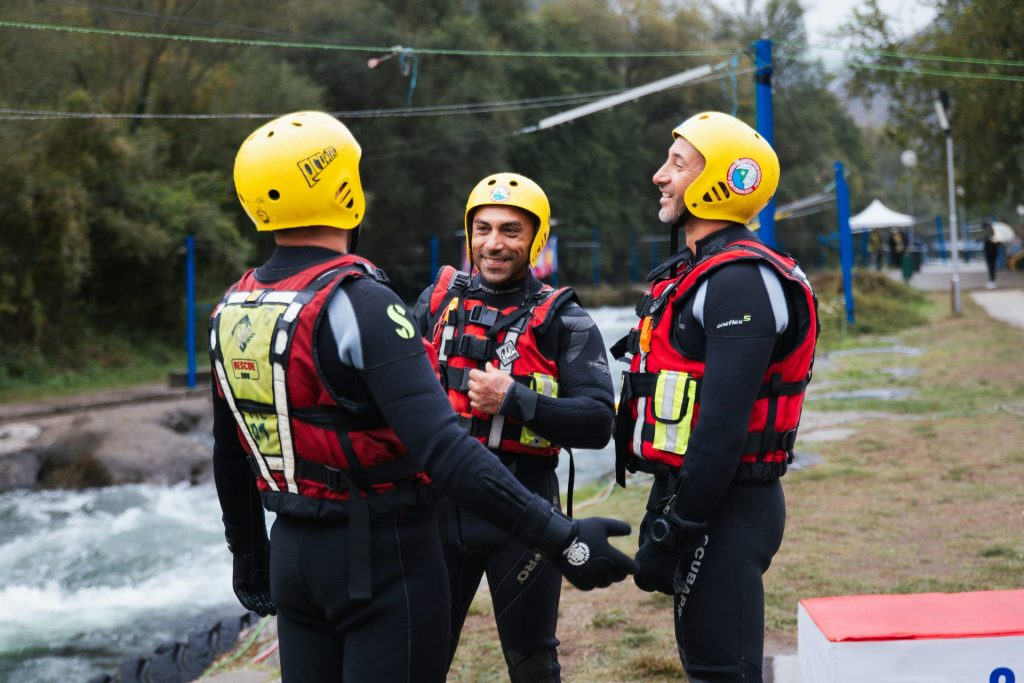 Drei Männer in gelben Helmen und Schwimmwesten unterhalten sich.