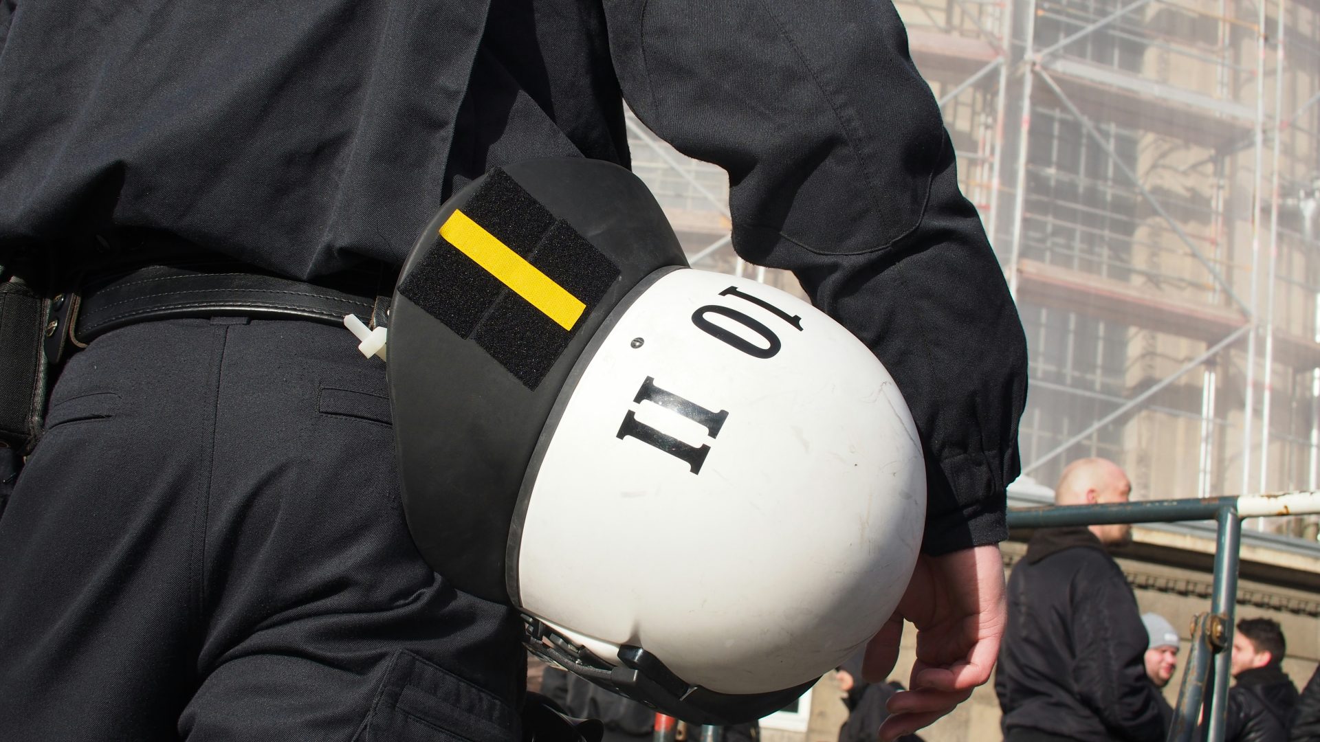 Ein Polizist hält einen weißen Helm in der Hand